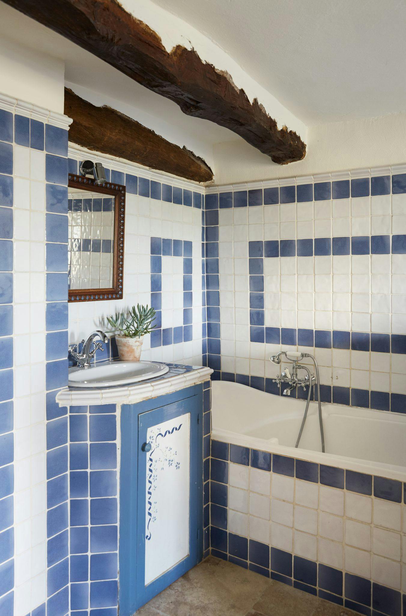 Bathroom with blue tiles and rectangular motifs and bathtub