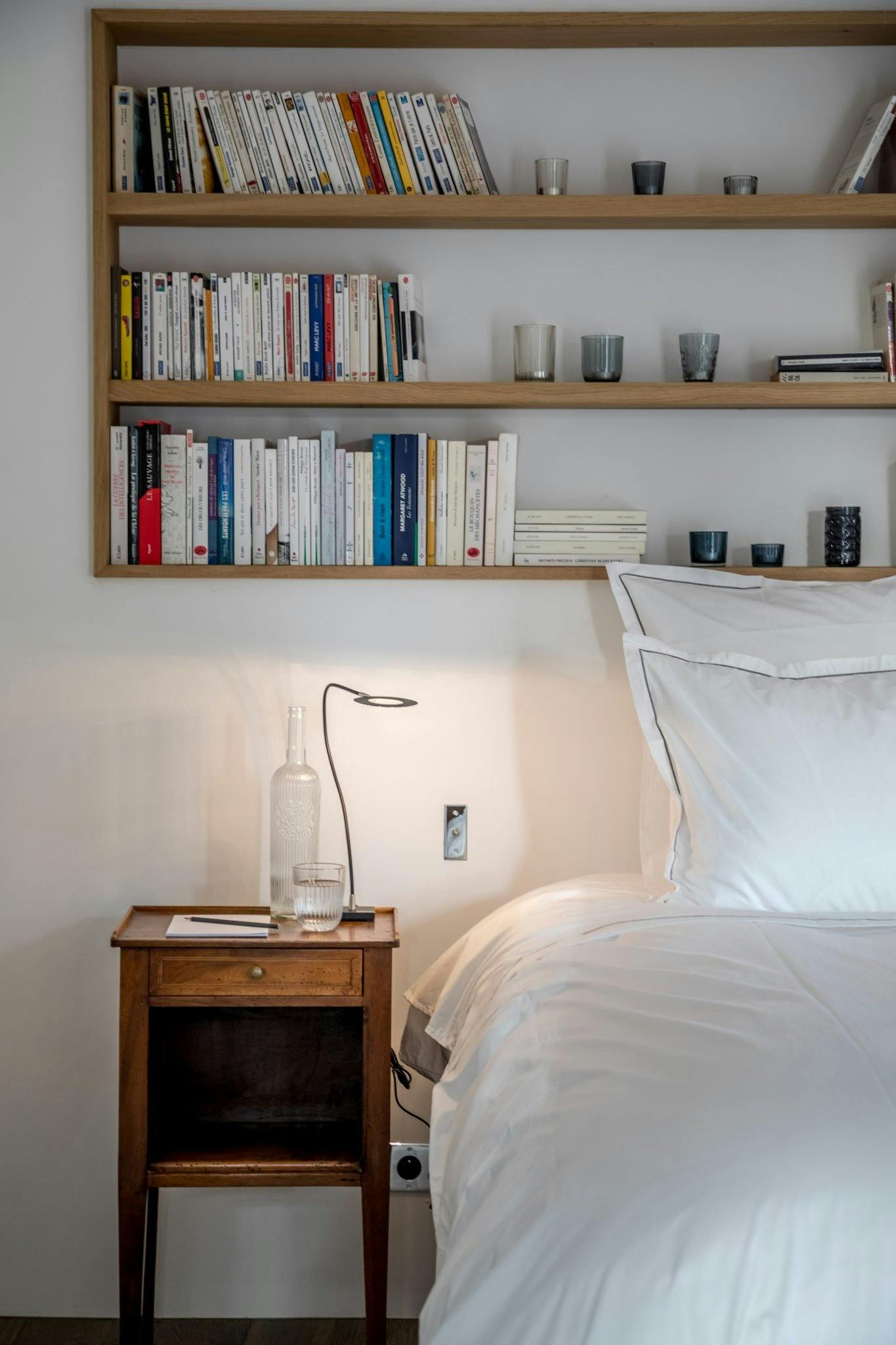 Bedroom topped by a bookshelf and wooden bedside table