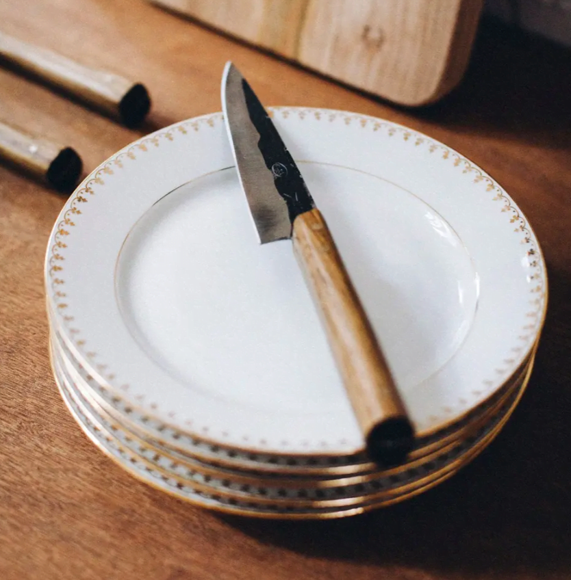 handmade paring knife on a pile of white plates