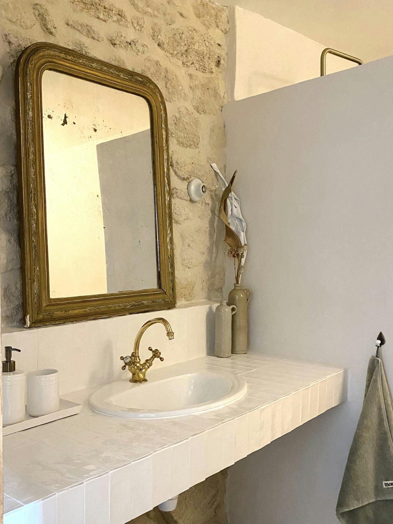 Lavabo et miroir ancien dans un décor de murs en pierre et de faïence