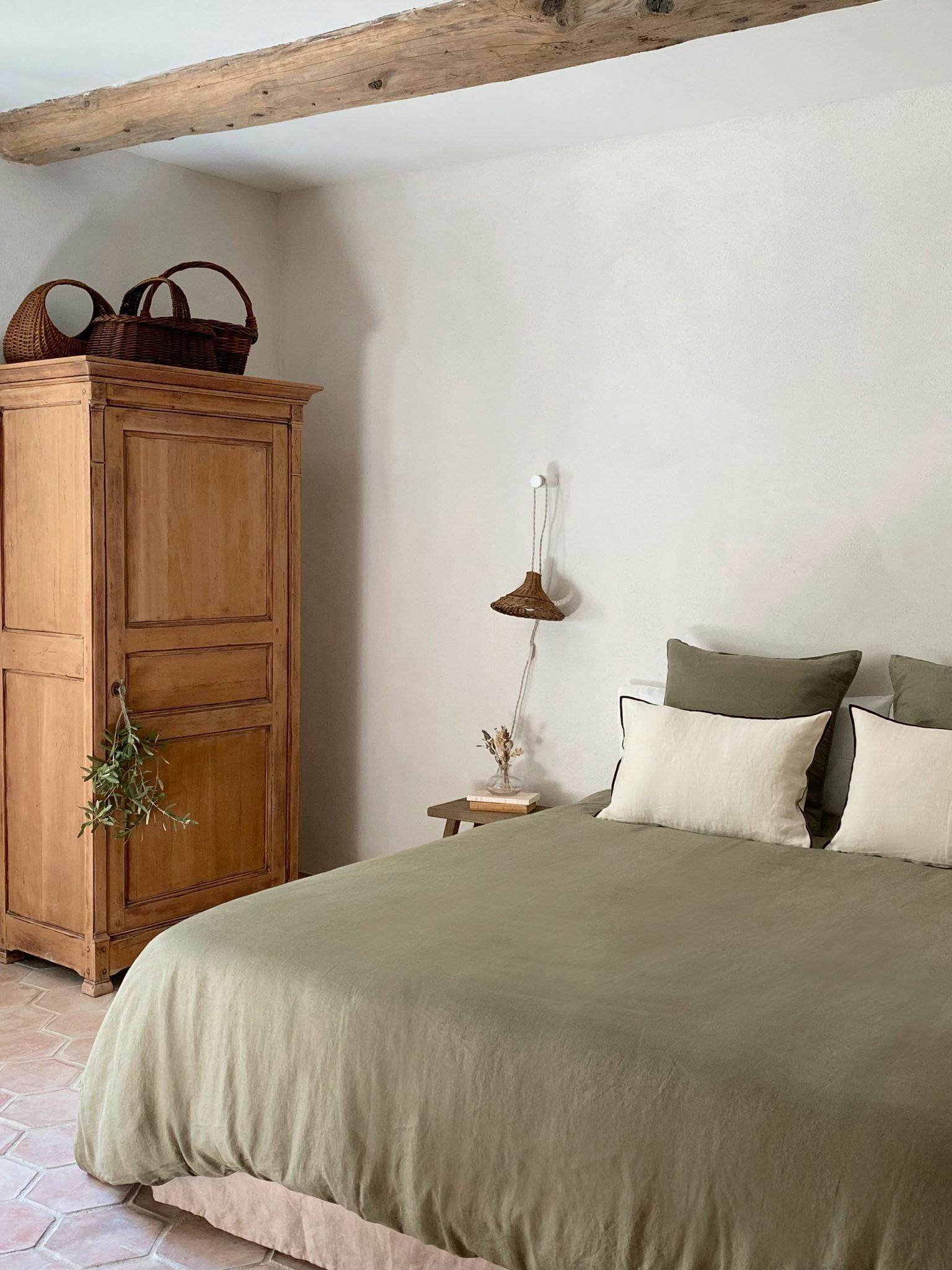 Murs à la chaux, lit double et draps en lin verts, armoire provençale
