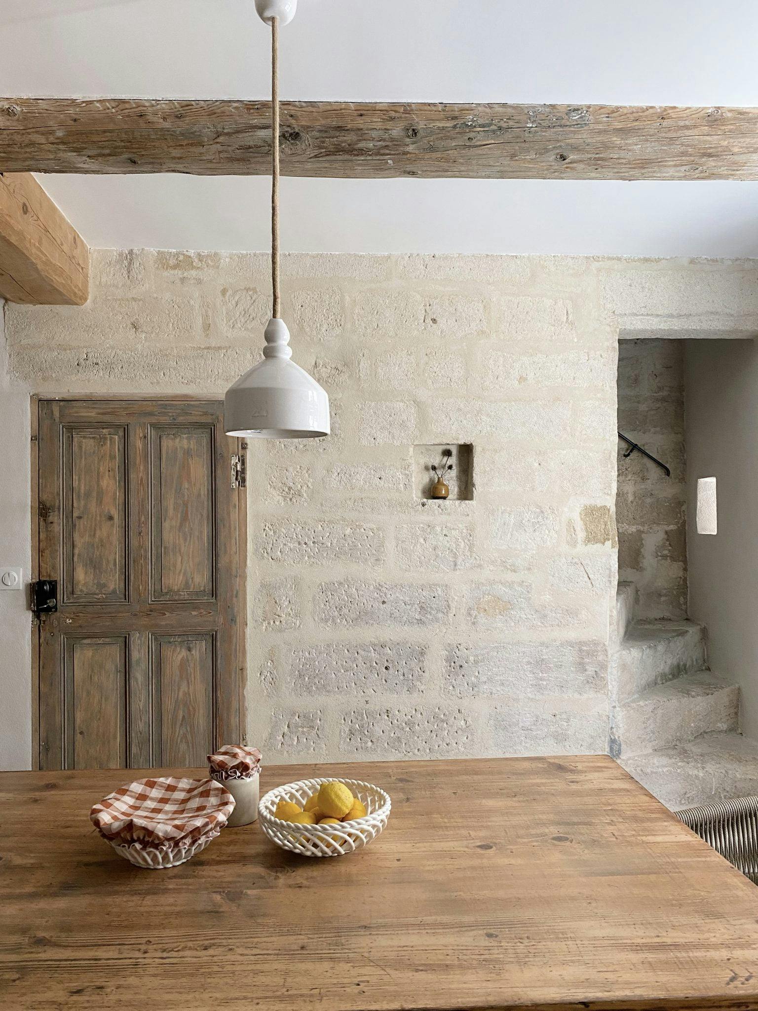 Grande table de ferme dans une pièce lumineuse en pierre et bois