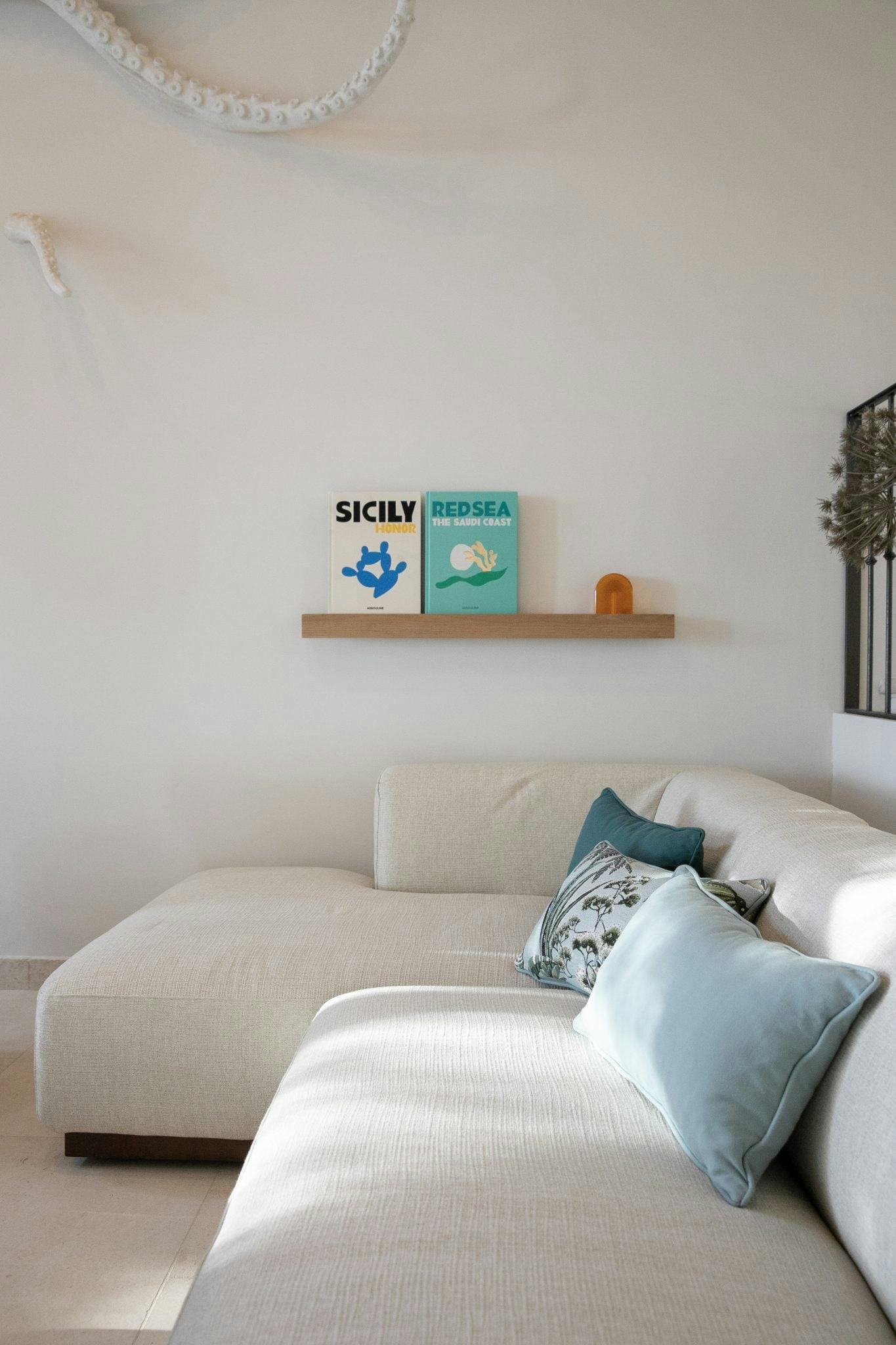 Salon : canapé blanc moderne et décoration (coussins et livres) dans les tons bleu