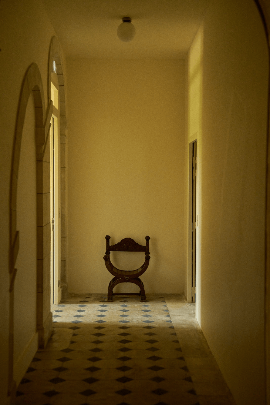 Vue depuis l'un des couloirs du château : fauteuil, carrelage blanc et bleu, murs blancs