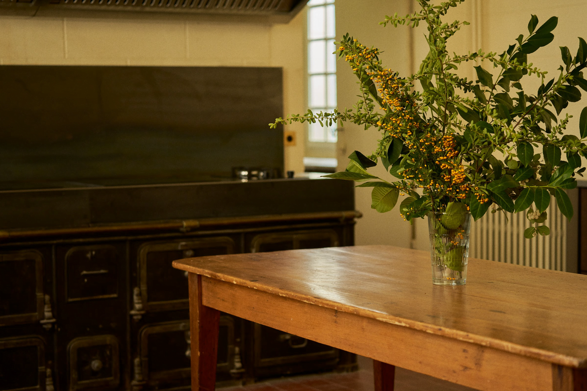 Wooden kitchen table with a bouquet of flowers, stove in the background