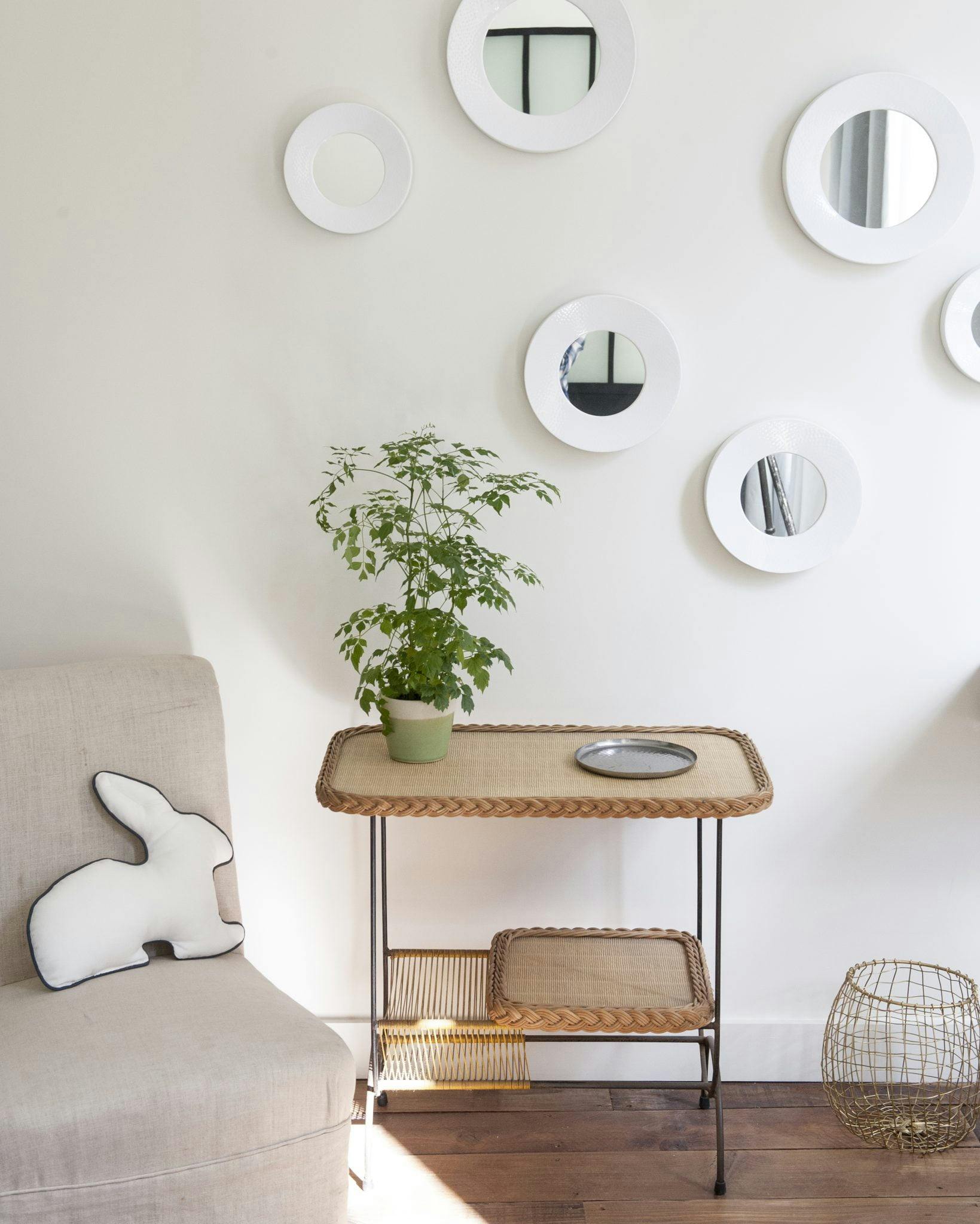 Détail d'une table en bois, miroirs sur mur blanc.