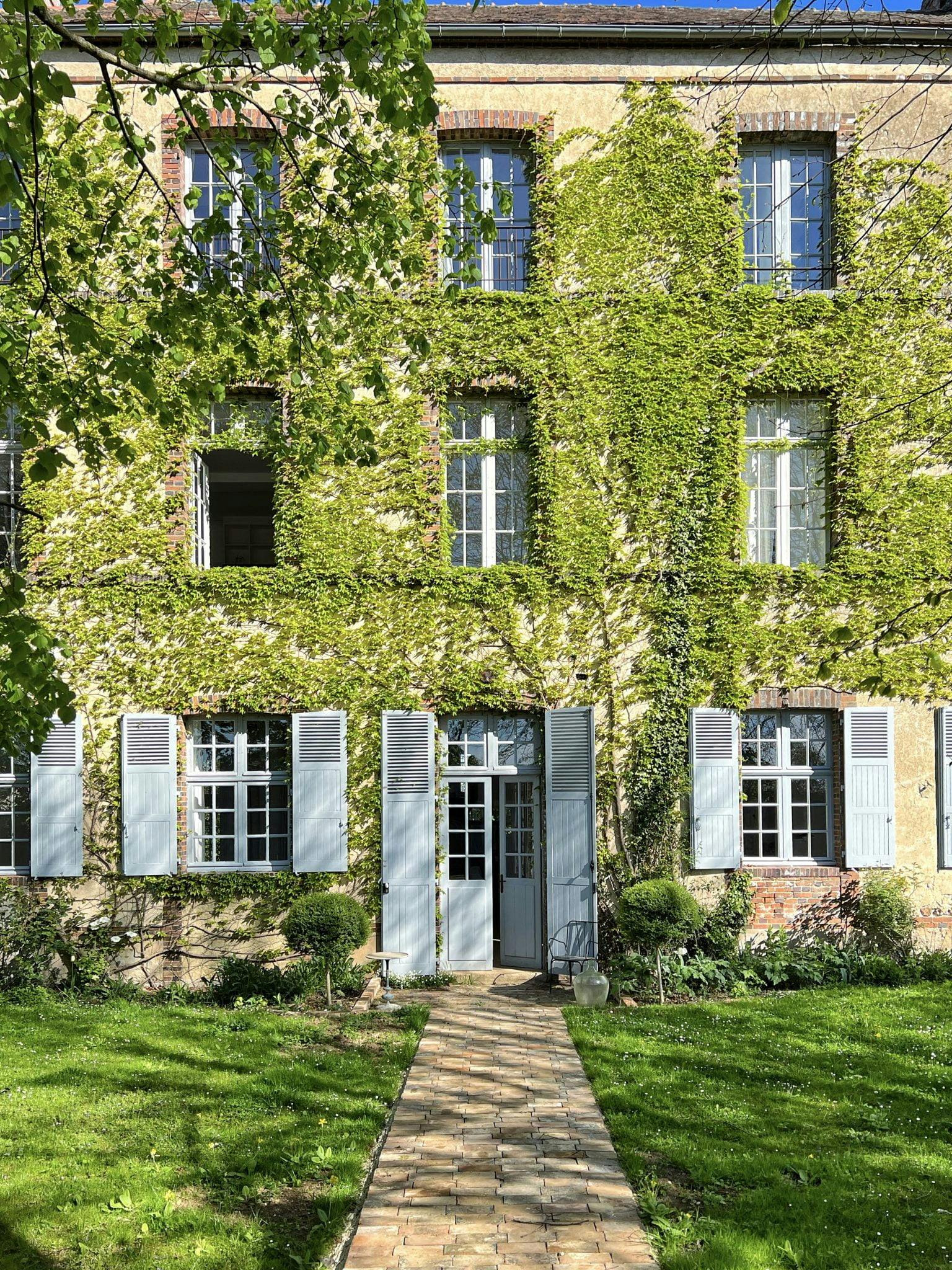 The facade of the Couvent des Ormes, lawn, sky blue shutters, and climbing ivy