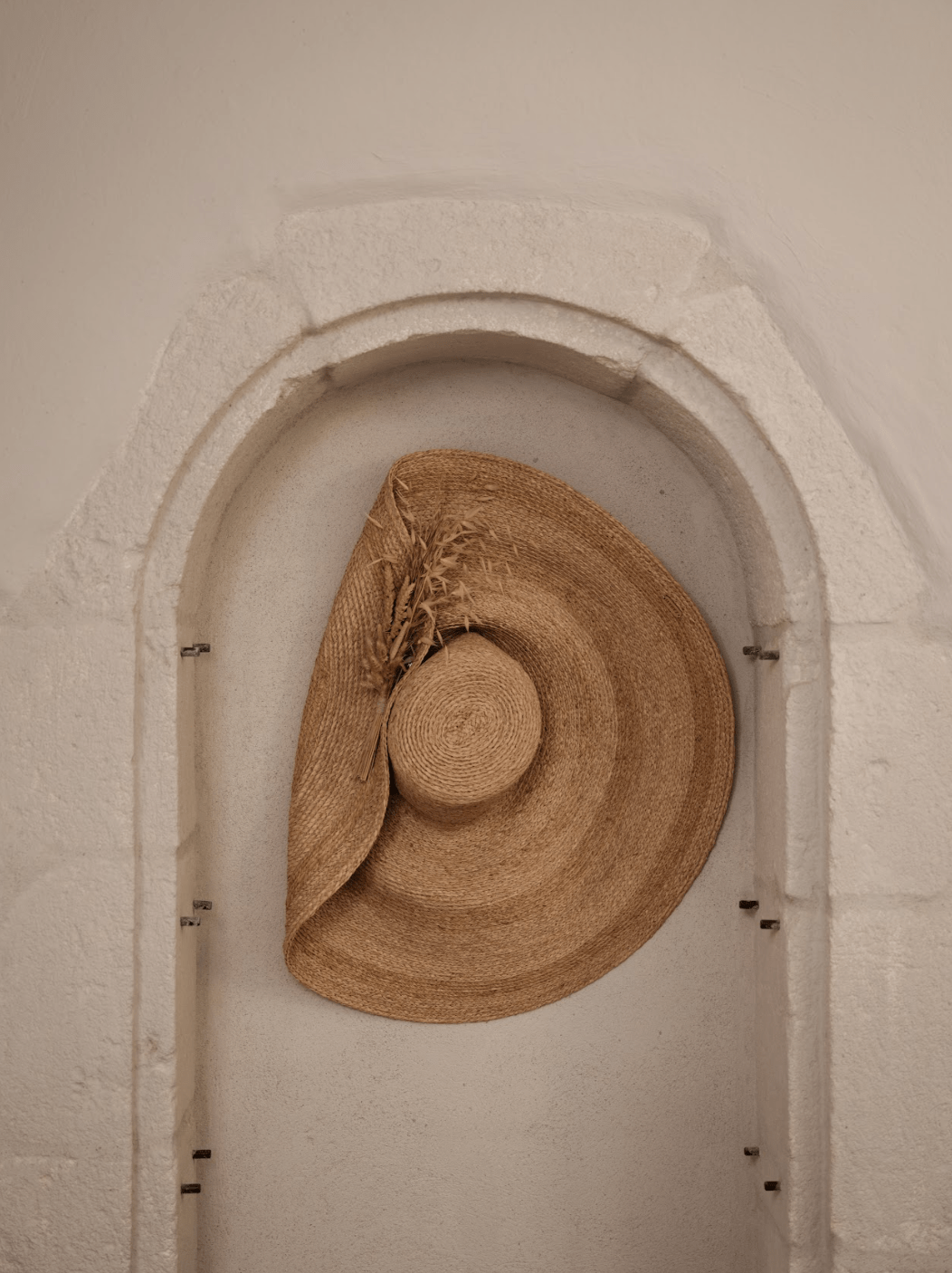 Chapeau de paille accroché sur un mur de pierres à la Maison des Remparts.