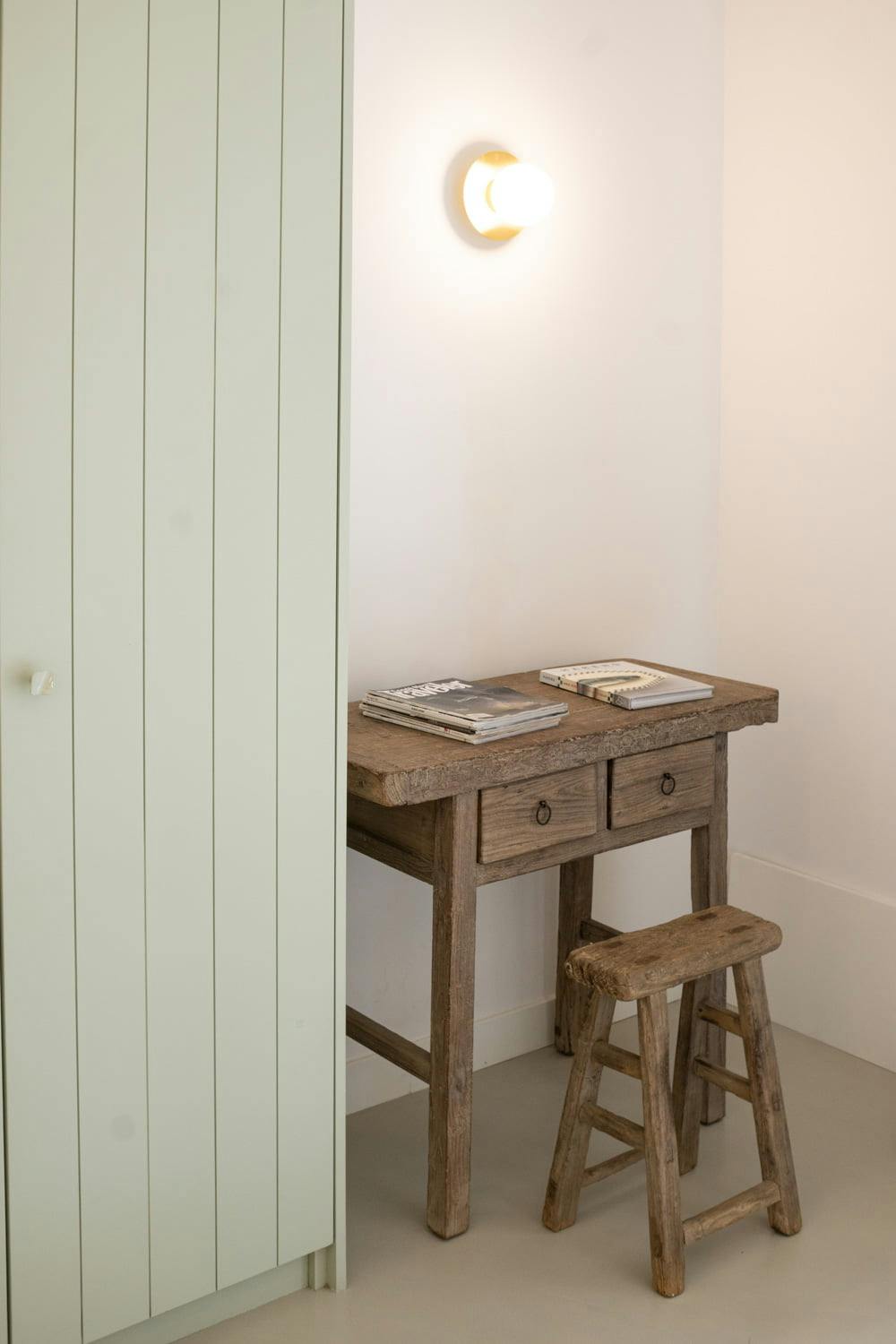 Petit bureau en bois près d'un mur vert pâle