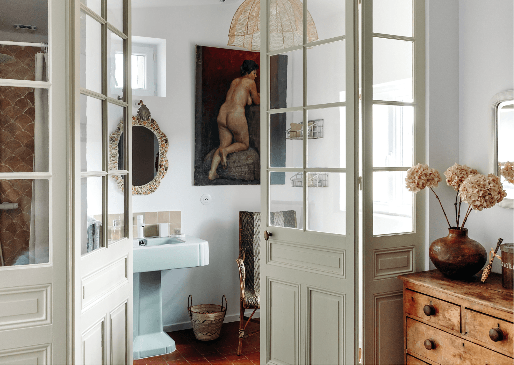 The bathroom: terracotta tiles, glass door, mirror, painting