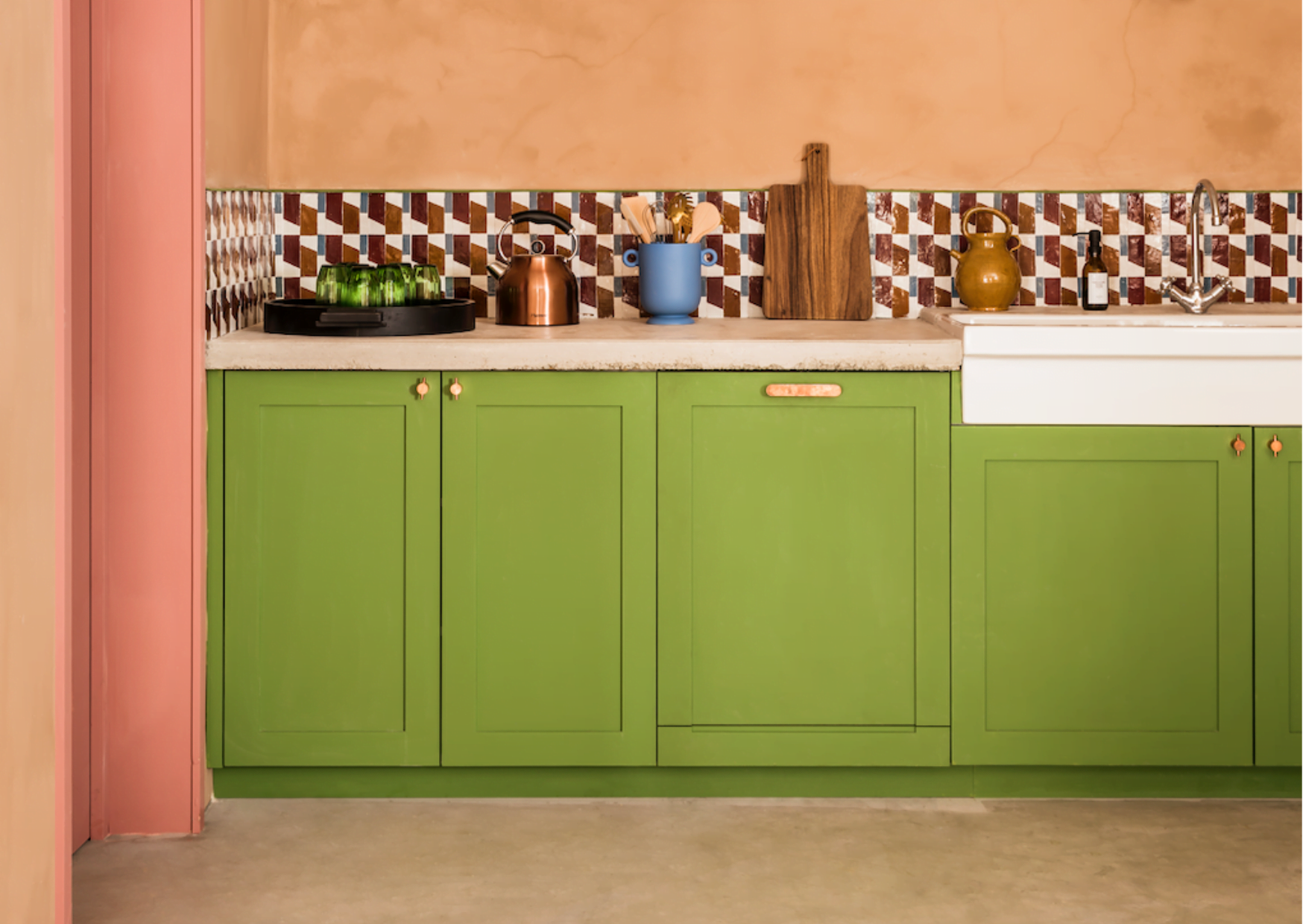 The kitchen of the holiday house at the Manufacture Royale de Lectoure: green furniture, orange wall