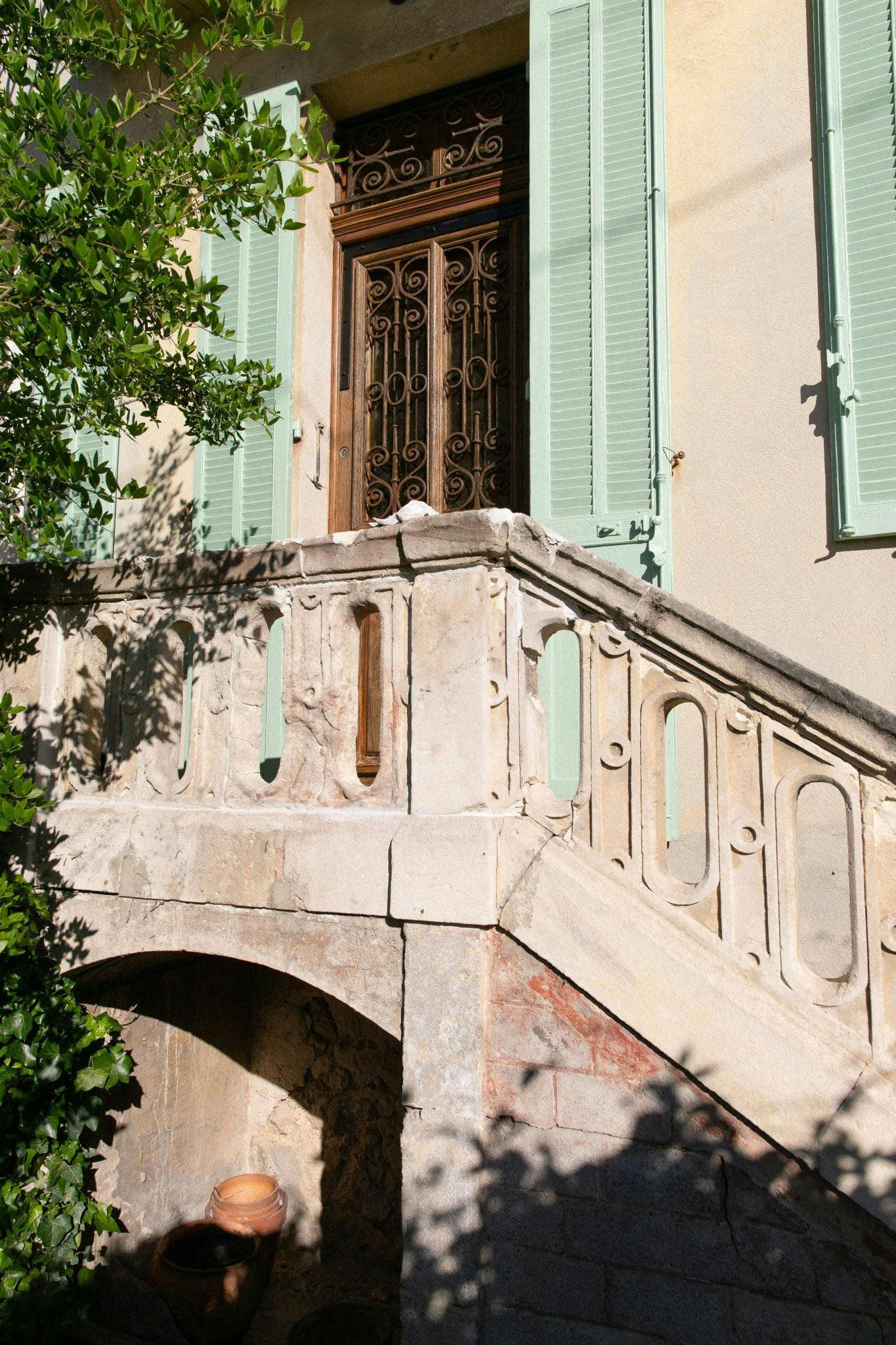 The mint green shutters echo the sea and the surrounding greenery.