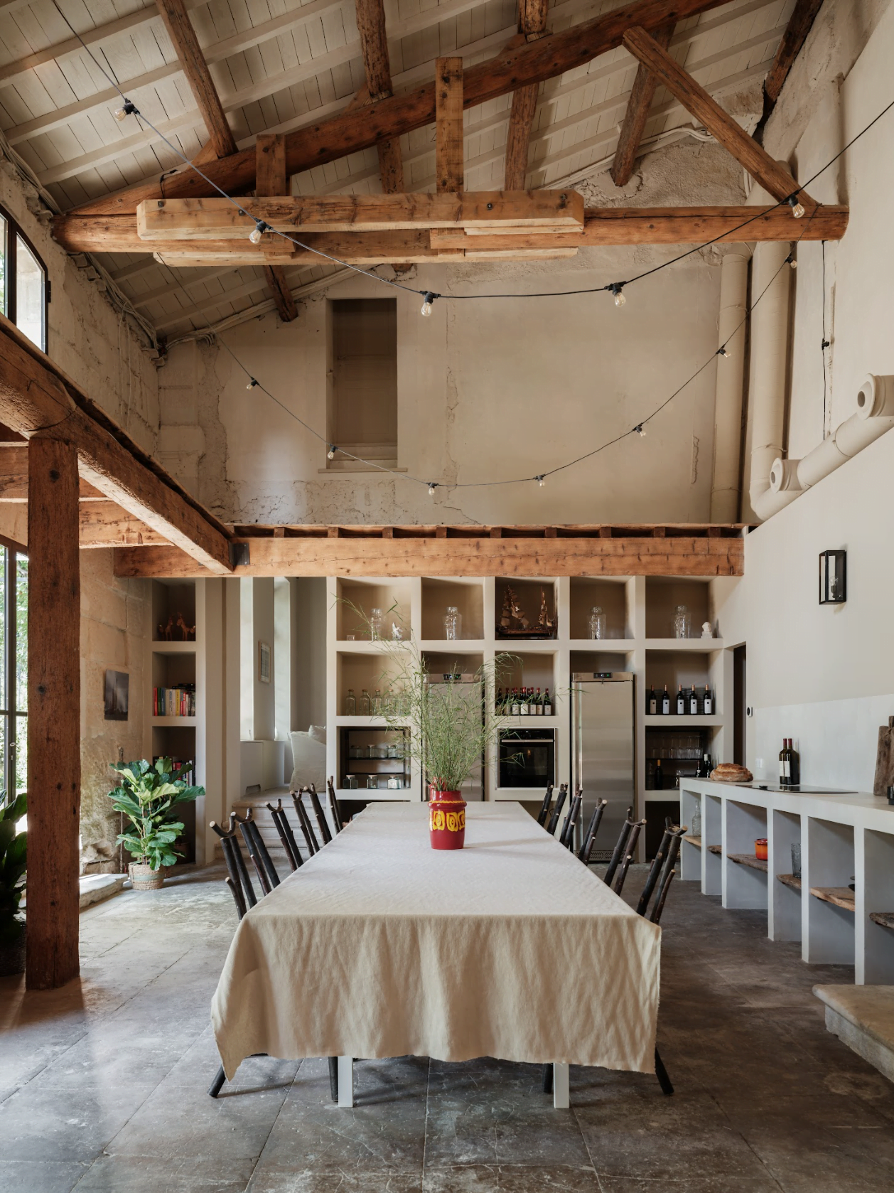 La grande table de la salle à manger. Nappe blanche, chaises, poutres en bois