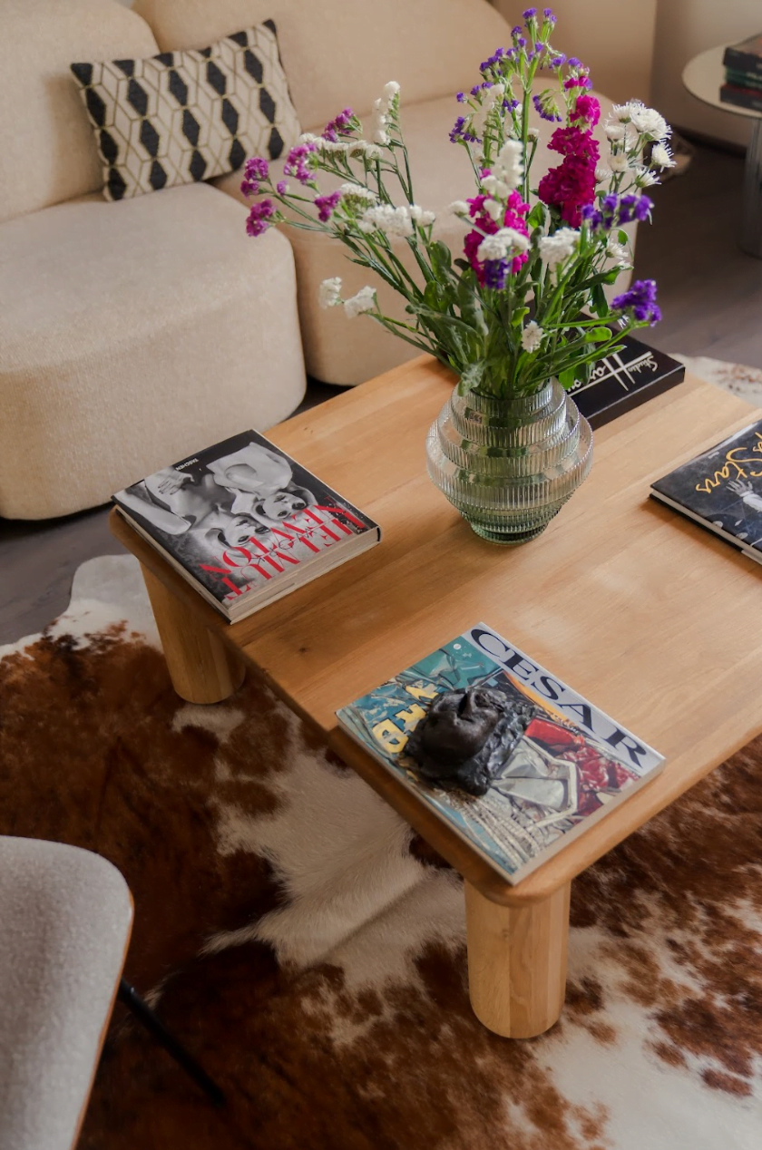 Détail de la table basse en bois du salon : magazines, bouquet de fleurs