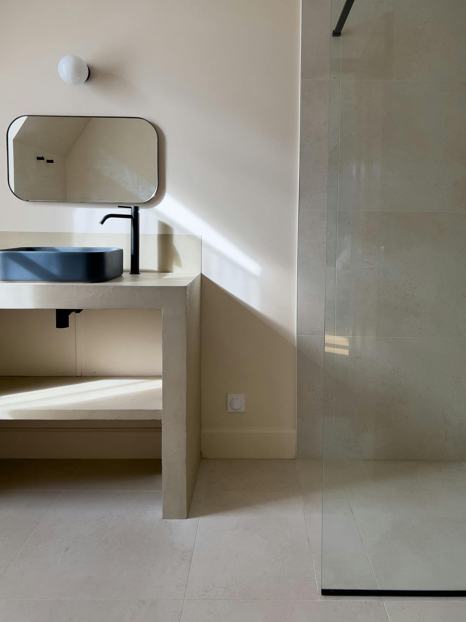 Detail of a bathroom: walk-in shower, sink, mirror.