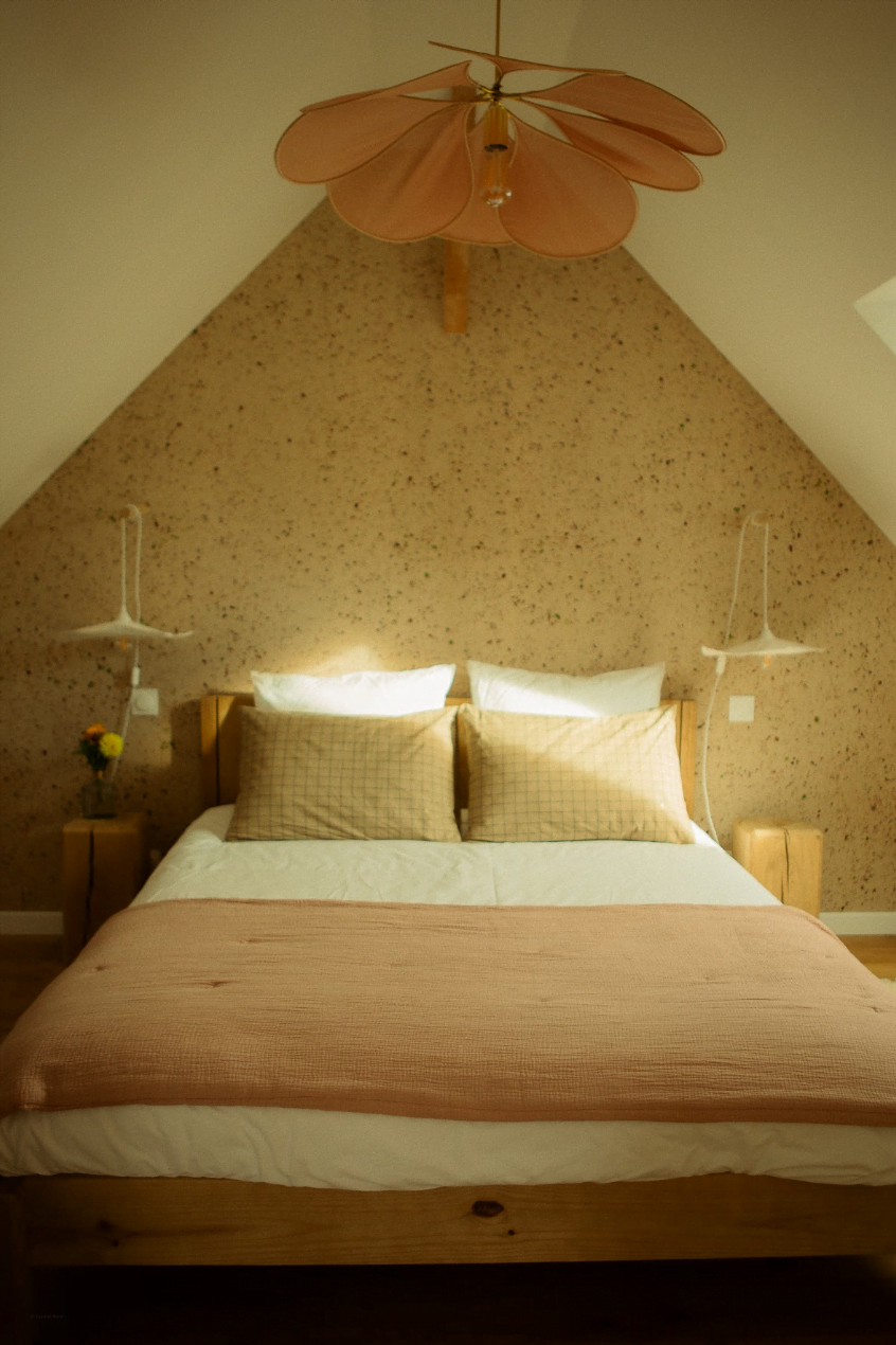 The double bed in the bedroom, terrazzo wall, and pendant light