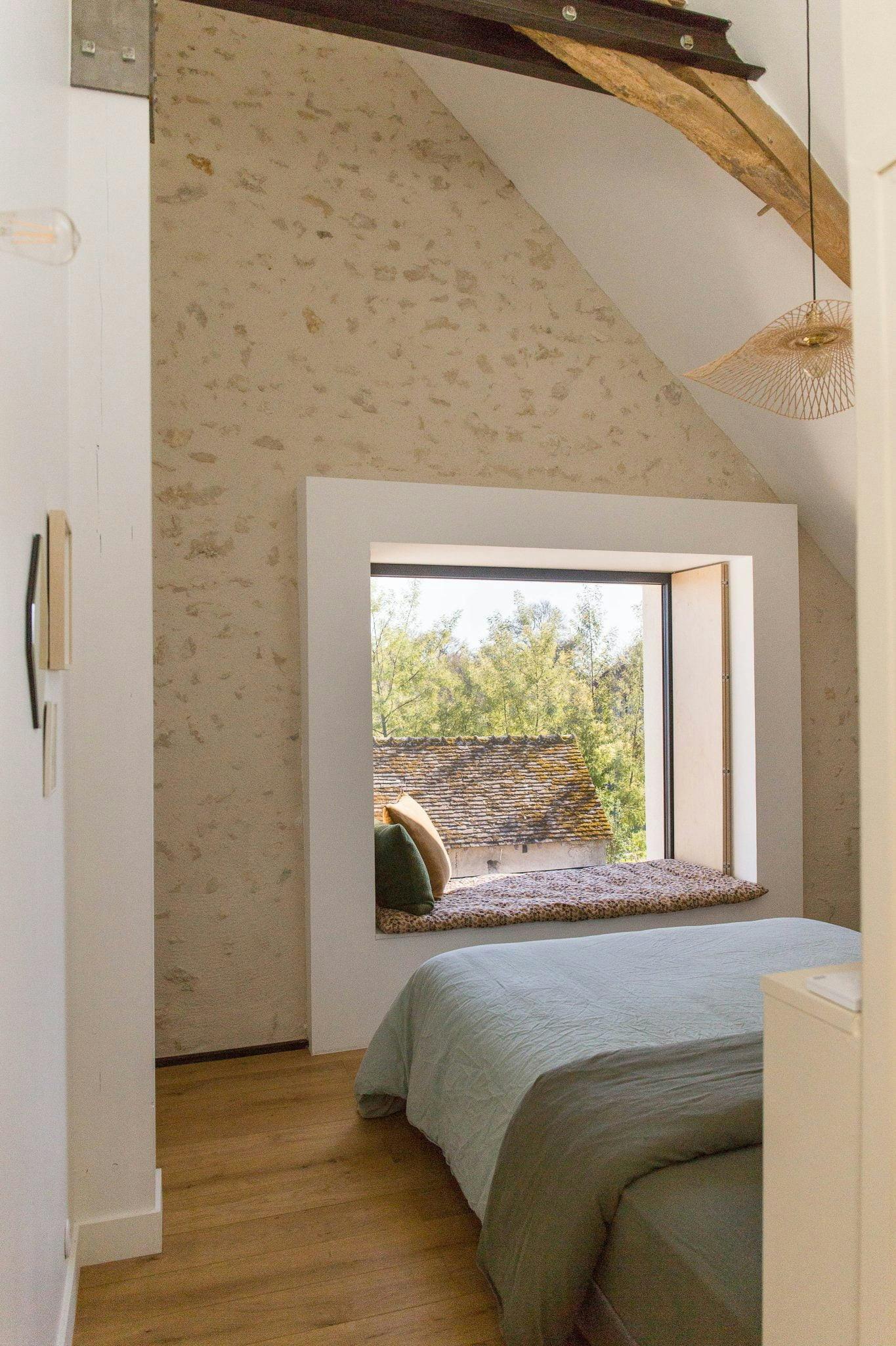 One of the bedrooms in the house: window-seat, bed, stone wall