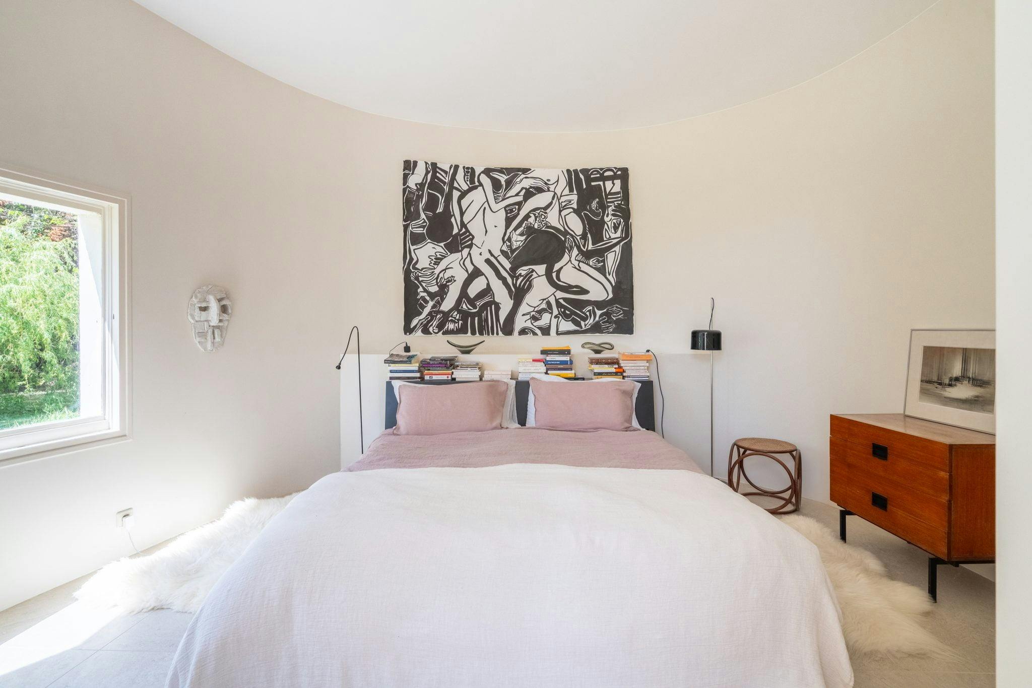 Chambre : draps roses et blancs, tableau au mur