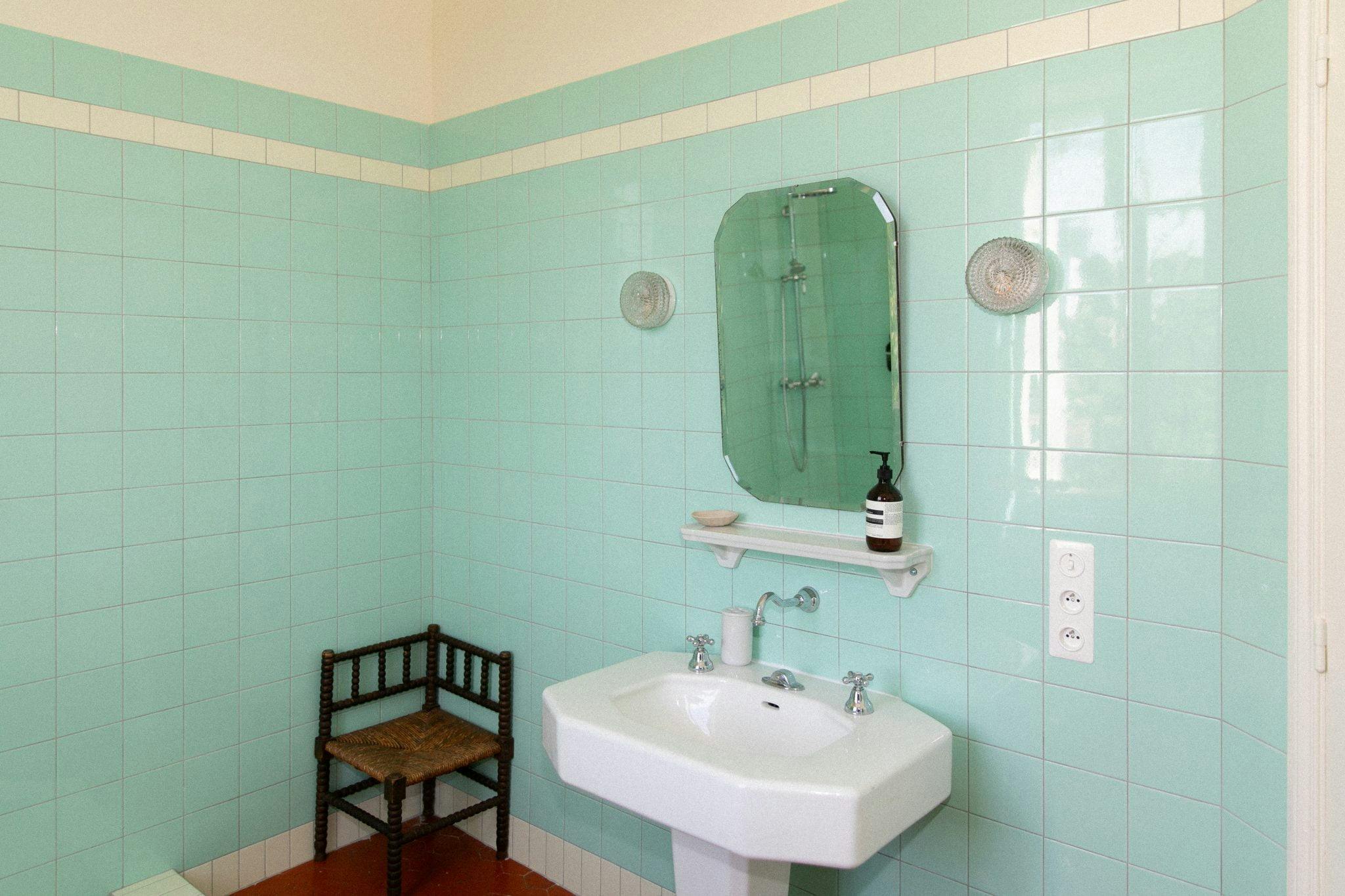 The bathroom in mint green: tiles, sink, chair