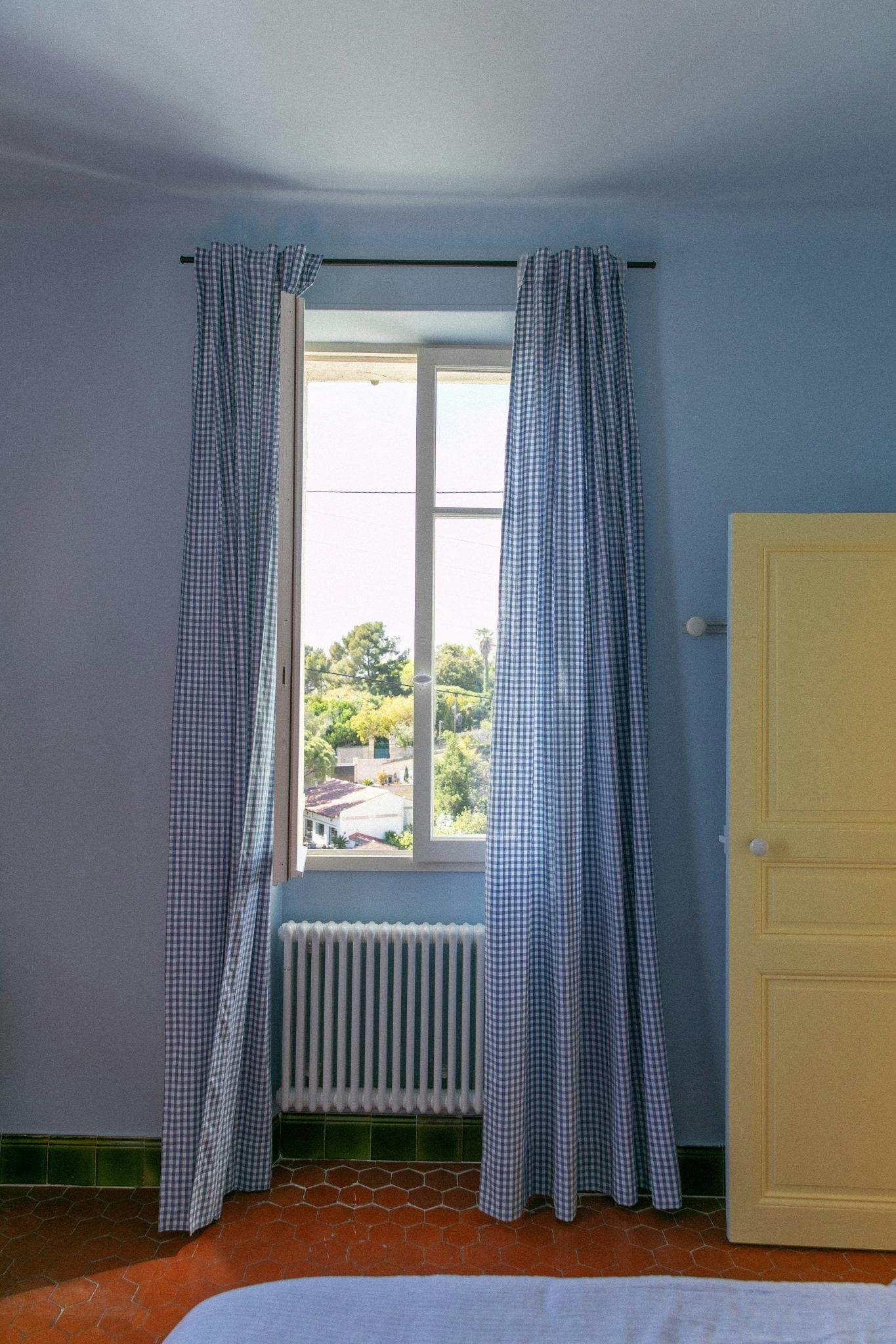 The blue bedroom: floor tiles, gingham curtains, yellow door