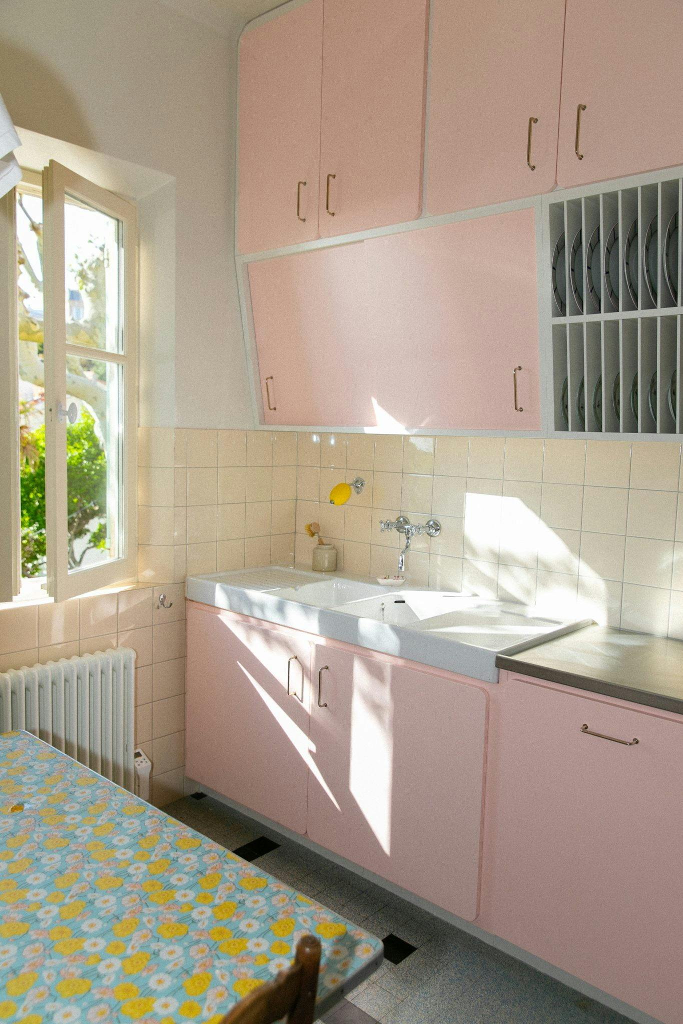 The pink kitchen: table with a floral tablecloth, window