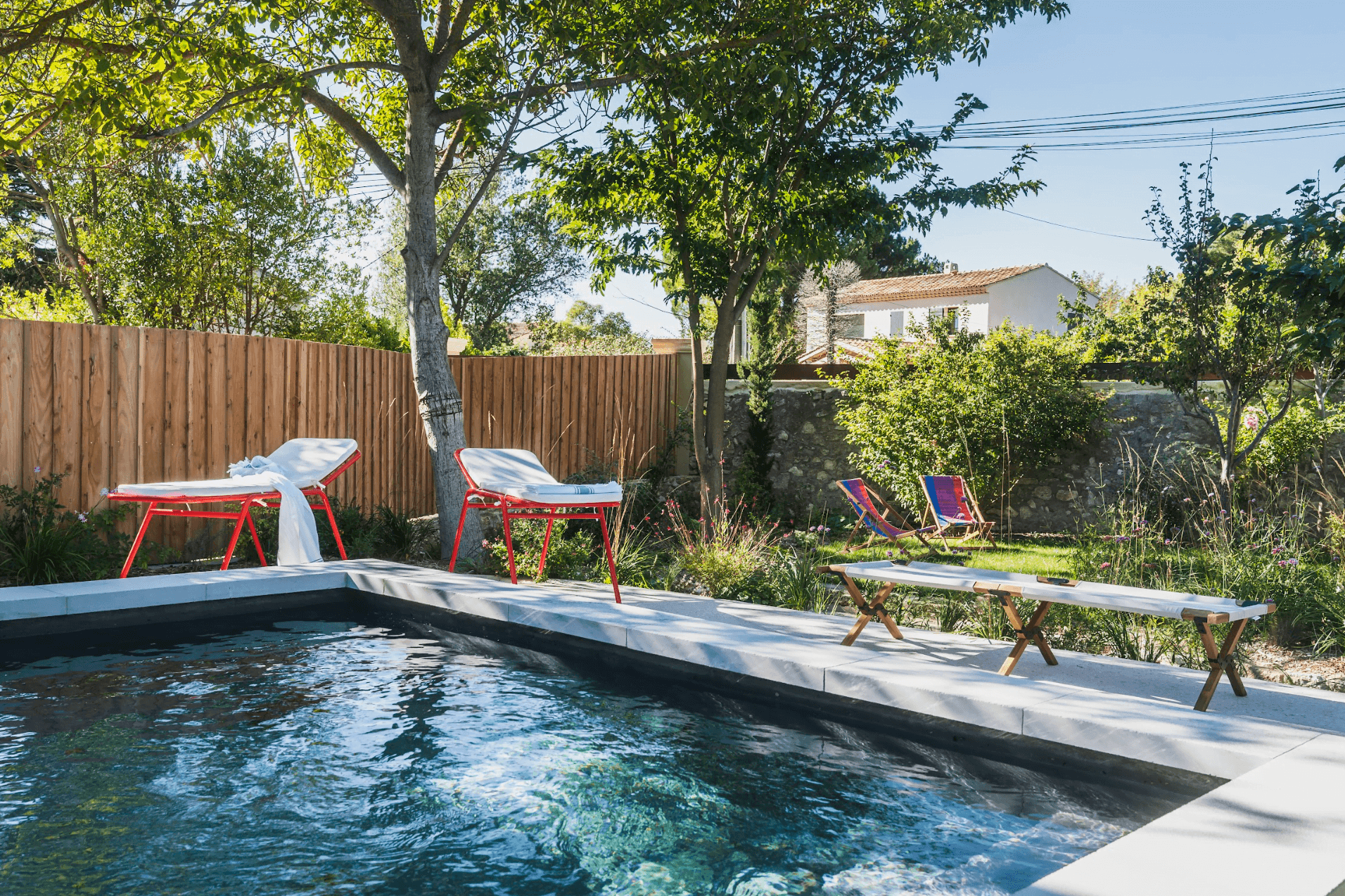 The small pool in the garden: deck chairs, trees, palisade.