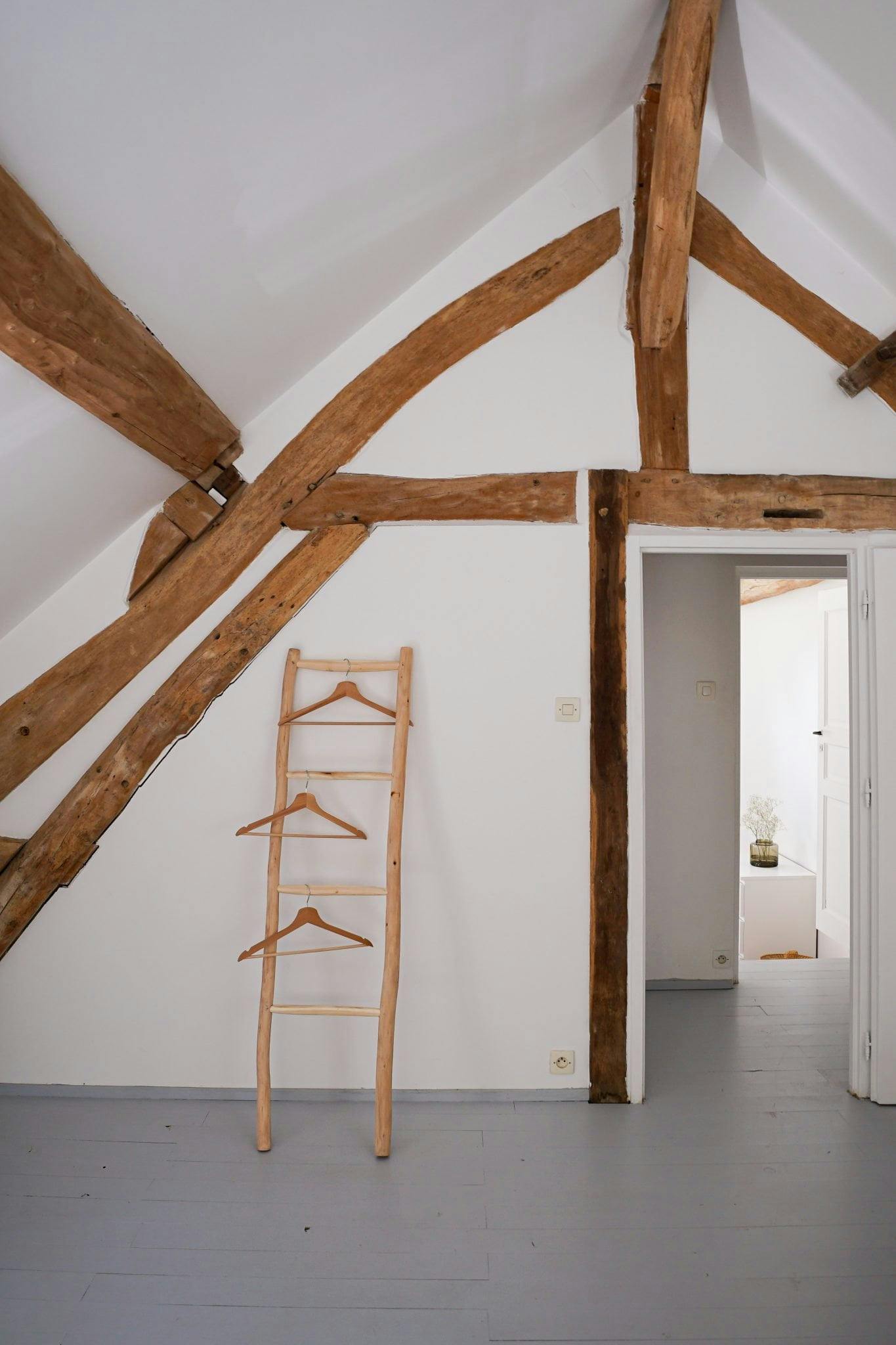 Wooden towel rack against a white wall, with wooden beams