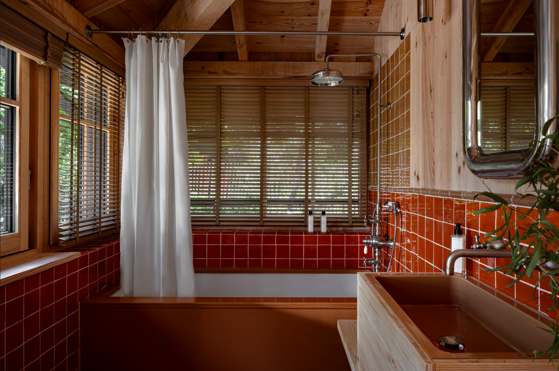 Baignoire, carreaux rouges, rideau blanc, fenêtre donnant sur le jardin