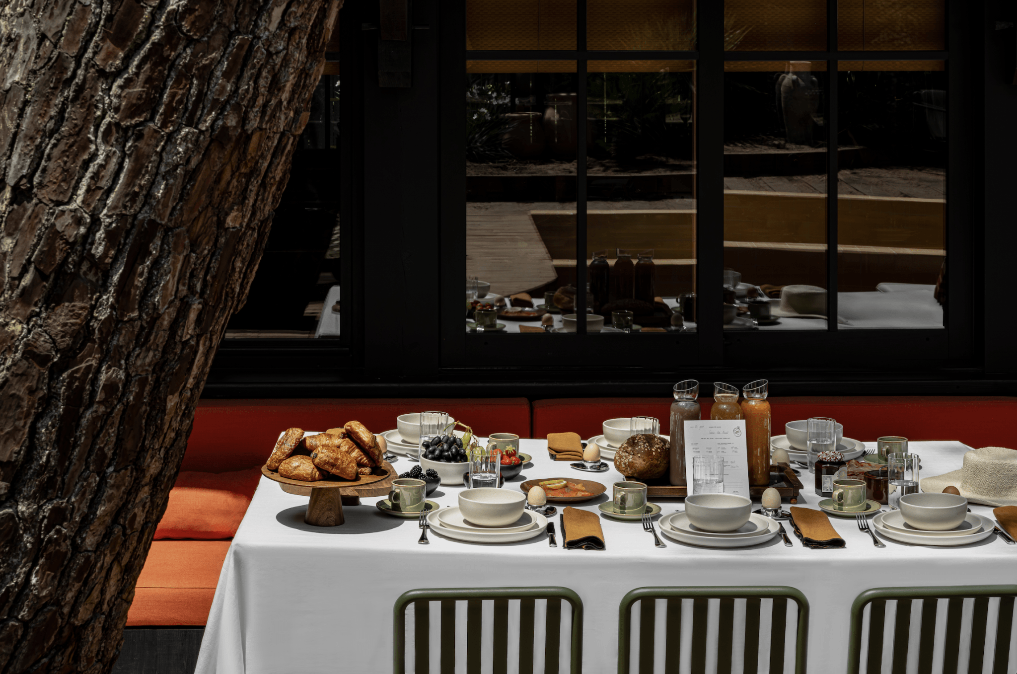 Table dressée dans le jardin, nappe blanche, plats et chaises