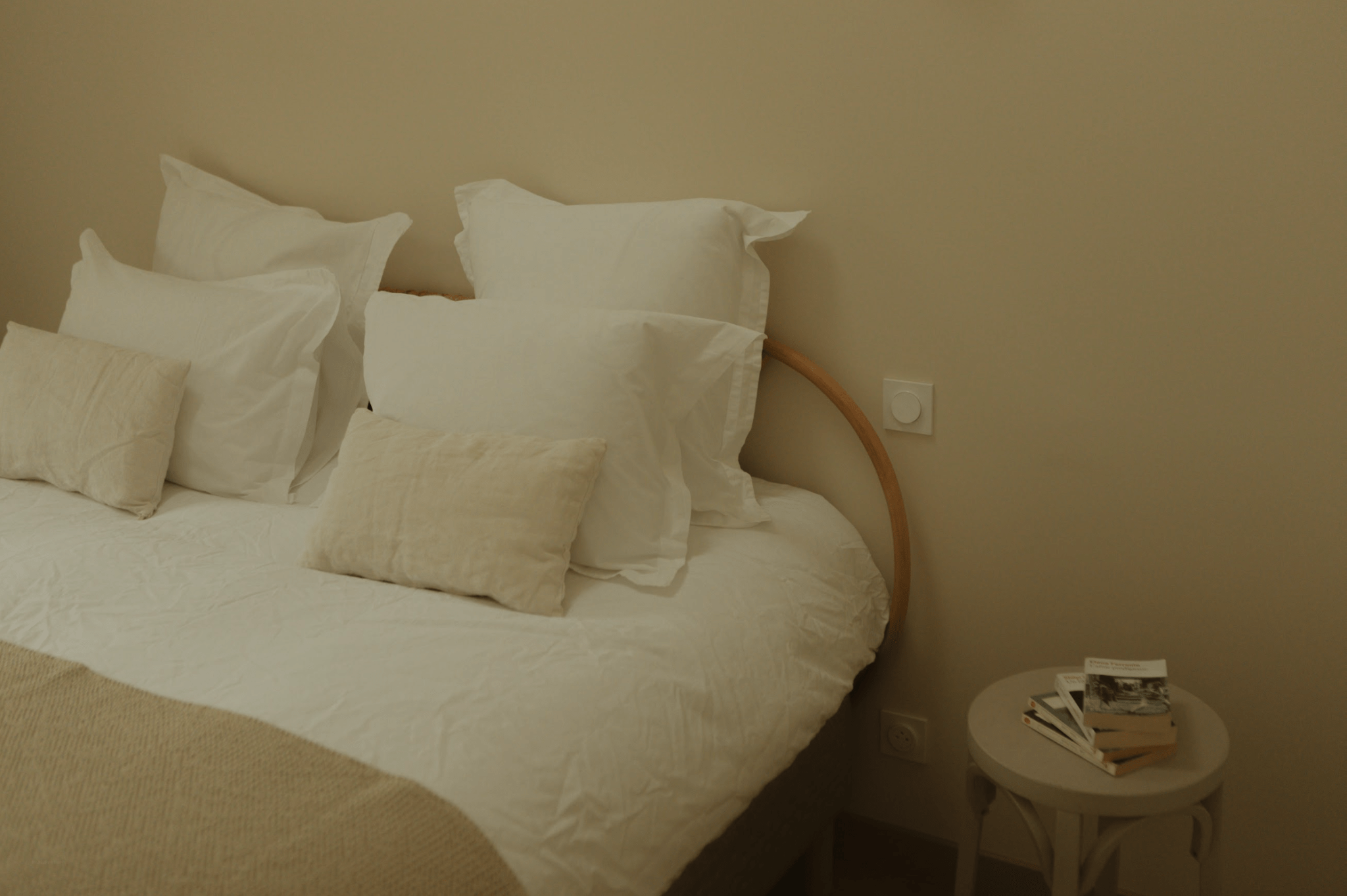 Détail d'un lit double dans une chambre. Draps blancs, table de nuit