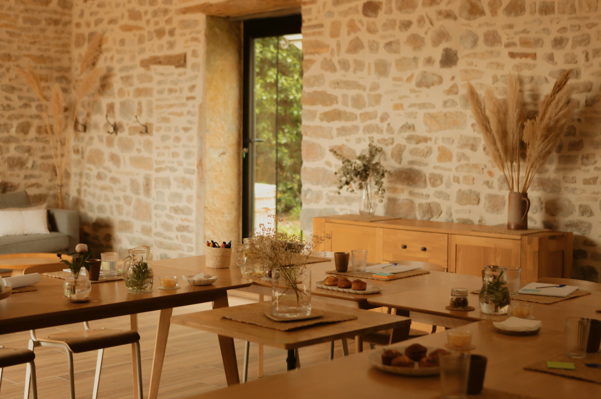 Grande pièce aux murs de pierre, grandes tables et chaises