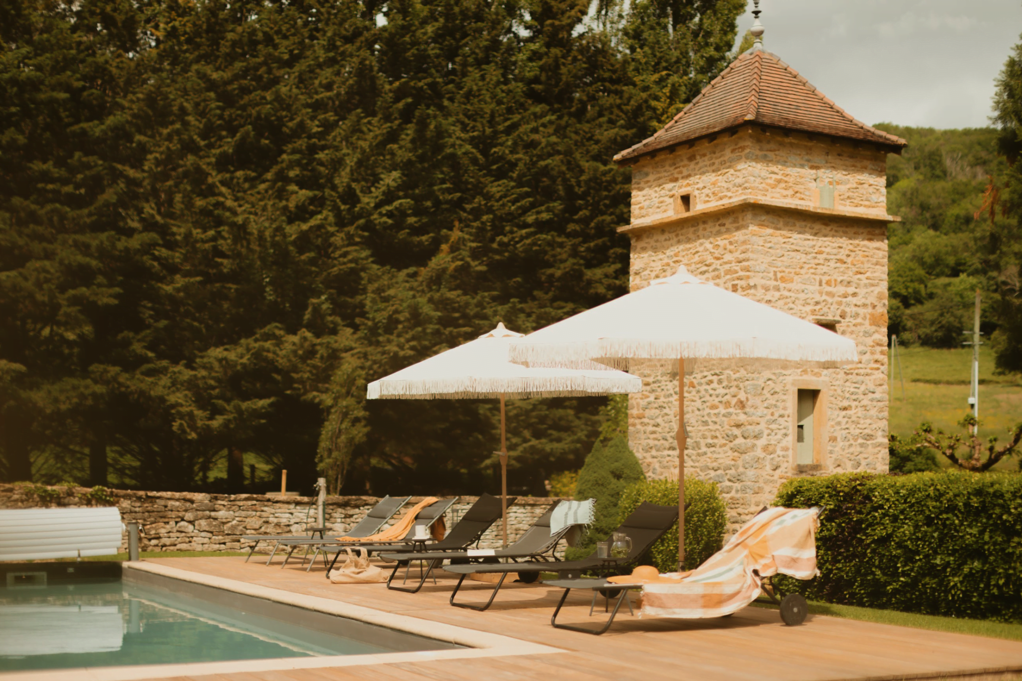 Pigeonnier en pierre, piscine, parasols blanc, transats