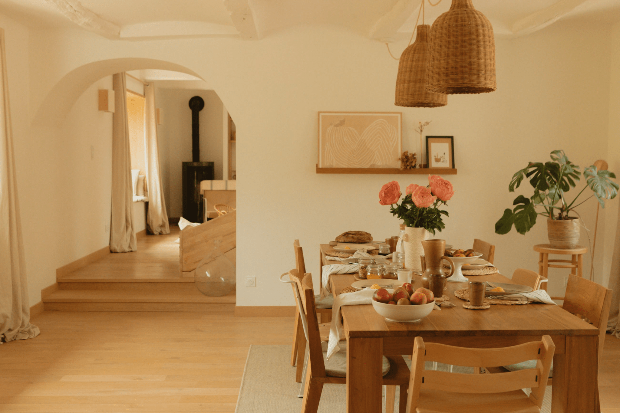 Grande table en bois dressée, chaises en bois, bouquet de fleurs, suspensions