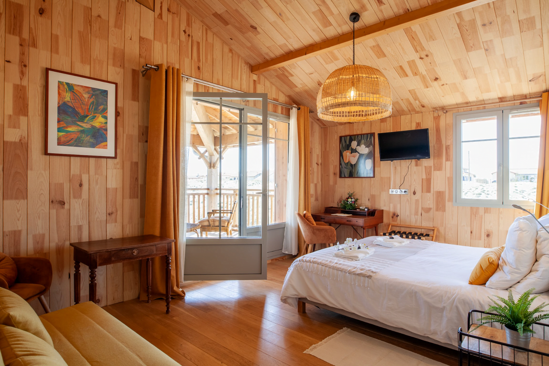 Bedroom with a double bed, white bed linens, wooden walls and beams, and a glass wall.