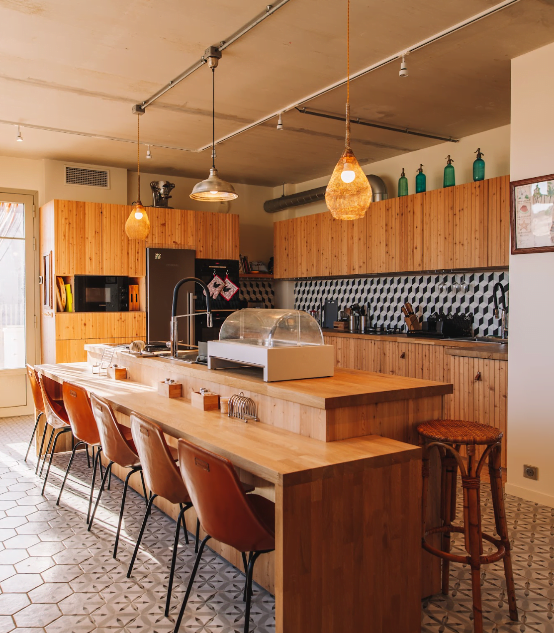 Large wooden kitchen island, bar stools, and pendant lights hanging from the ceiling.