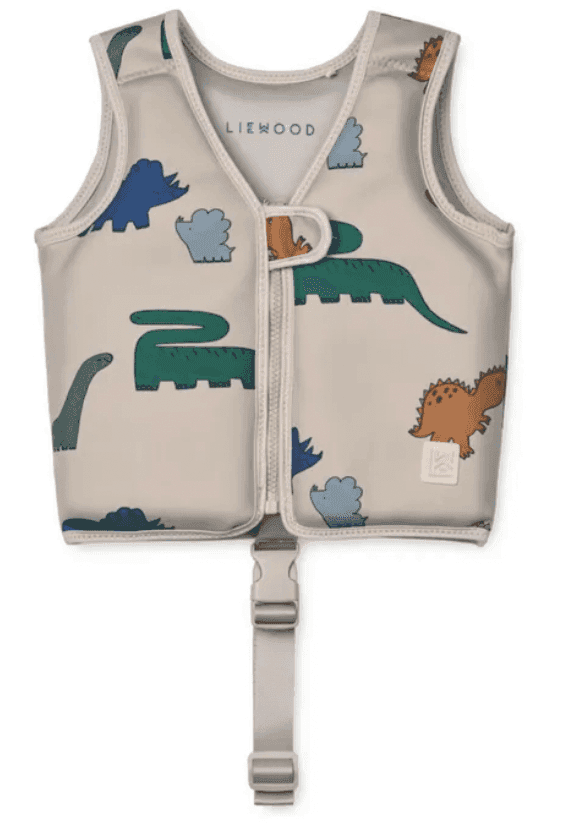 Gilet de sauvetage pour enfant avec motifs de dinosaures colorés, dont des dinosaures verts et bleus sur fond clair. Il est doté d'une fermeture éclair sur le devant et d'une sangle réglable avec une boucle en bas.