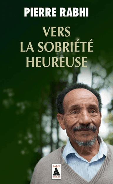 Couverture du livre intitulé "Vers la Sobriété Heureuse" de Pierre Rabhi, représentant un homme aux cheveux courts et à la barbe, vêtu d'une chemise à col et d'un pull, sur un fond naturel flou.