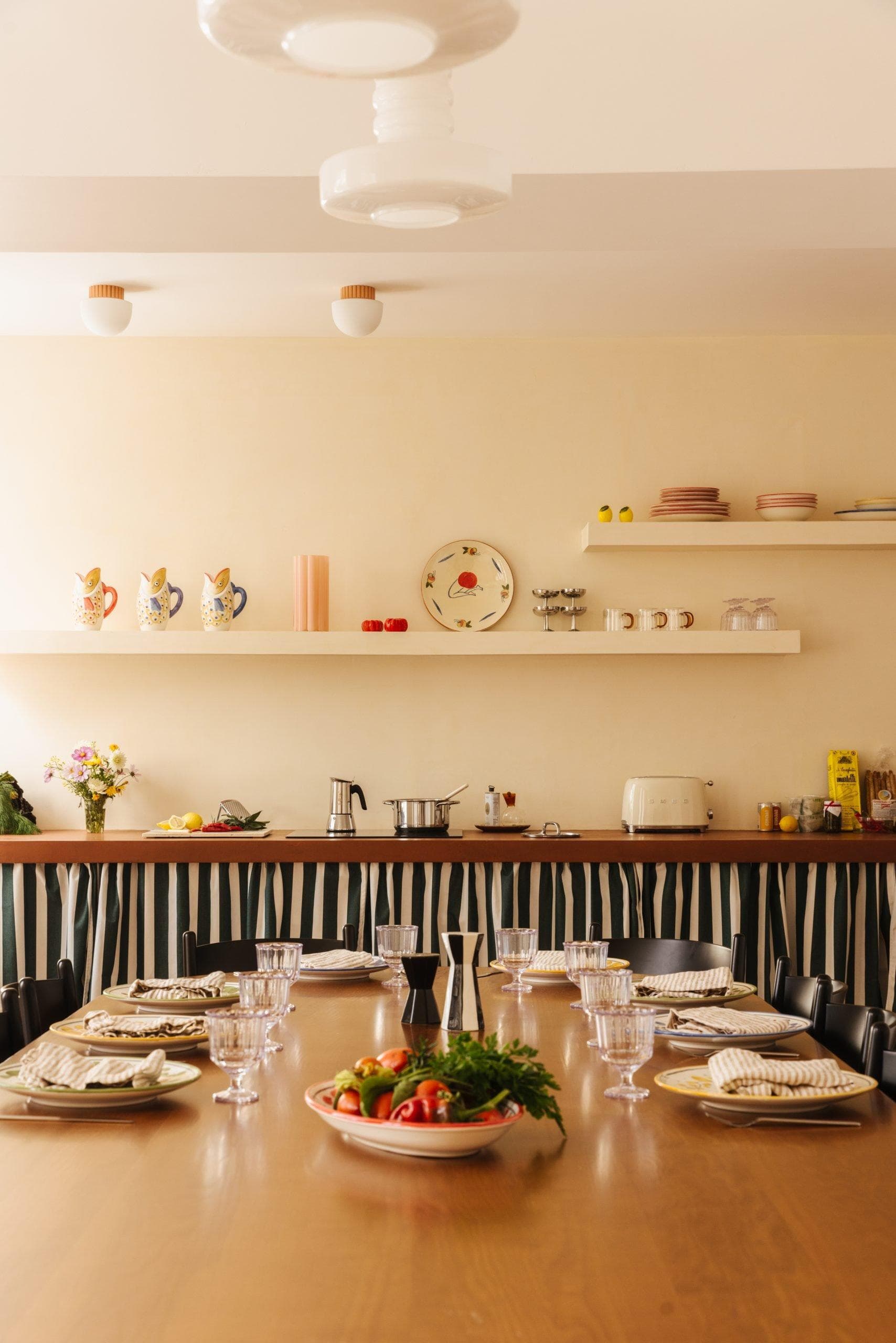large wooden table with dresser and kitchen utensils in the background